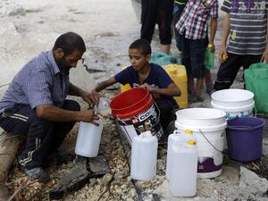 A Palestinian man and children fill containers with water from a broken main. (AFP)