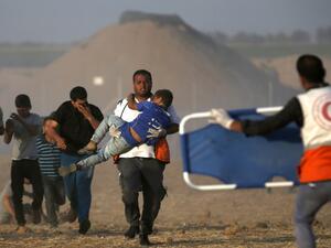 A Palestinian protester carries a child injured during a demonstration in front of Israeli forces along the border between the Gaza Strip and Israel, east of Khan Yunis in the southern Gaza Strip on June 22, 2018. (SAID KHATIB / AFP)