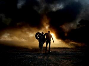 Palestinian protesters carry tyres as smoke billows from burning tyres at the Israel-Gaza border, east of Gaza city. (SAID KHATIB / AFP)