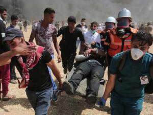 An injured Palestinian protestor is carried by fellow demonstrators during clashes with Israeli security forces near the border with Israel, east of Khan Yunis, in the southern Gaza Strip, on April 6, 2018 (AFP/SAID KHATIB)