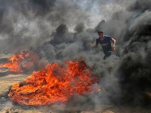 A Palestinian walks in the smoke billowing from burning tires during clashes with Israeli soldiers along border with Gaza strip east of Khan Younis, May 14, 2018 (AFP Photo/ Said Khatib) 