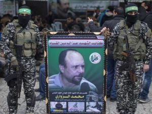Members of the Ezzedine al-Qassam Brigades, the military wing of Hamas, hold a banner bearing a portrait of Mohammed al-Zoari in Gaza City on December 18, 2016. (AFP/Mahmud Hams)