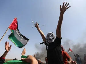 Palestinian demonstrators wave their national flag and shout slogans against Israeli security forces during a protest on the Israel-Gaza border in the northern Gaza Strip on April 6, 2018. (AFP/Mohammed Abed)