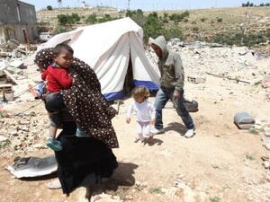 A Palestinian family whose house was demolished by Israeli bulldozers walk past a tent on April 21, 2015, in the southern West Bank village of Ad-Deirat Rifaiyya. (AFP/Hazem Bader)