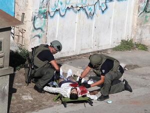Israeli security forces inspect the body of a Palestinian man who stabbed and lightly wounded an Israeli border guard before being shot dead in the Israeli occupied West Bank city of Hebron, on October 29, 2015. (AFP / Hazem Bader)  