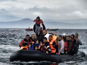 A man holds up a young boy as a boat carrying migrants and refugees arrives at the Greek island of Lesbos after crossing the Aegean sea from Turkey on October 21, 2015 (AFP/ File Photo)
