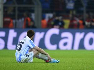 Malaga player slumps after the controversial Champions League defeat (AFP/John MacDougall)