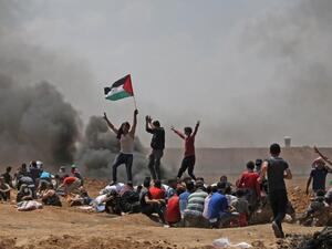 Palestinians wave their national flag as they demonstrate near the border between Israel and the Gaza Strip /AFP