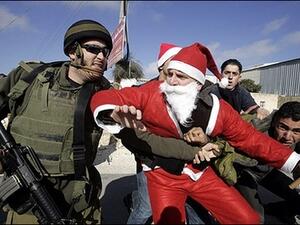 An Israeli soldier tackles a Palestinian protester dressed as Santa Claus or Father Christmas during at a protest against Israel’s separation barrier in the village of Umm Salamunah near the biblical West Bank town of Bethlehem. Israeli guards beat five demonstrators during the protest on Friday, organisers said.
Dec. 23, 2007 (AFP/Musa al-Shaer)