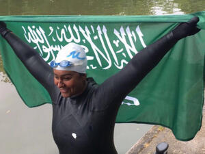 Mariam Binladen triumphantly holds the Saudi flag after completing the 101-mile swim of the Thames. (Twitter)
