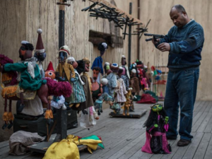 Puppeteer Khaled Essa arranges a string puppet at backstage prior to an open-air show for World Heritage Day in the old town of Cairo. (News.xinhuanet.com)
