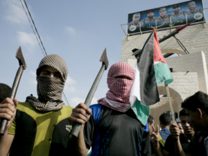 Palestinian students in checkered keffiyehs holding axes. (photo: AFP)  Palestinian students in checkered keffiyehs holding axes. (photo: AFP)