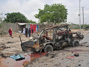 A soldier stands guard near a car destroyed in a bomb attack in Mogadishu, Somalia, 10 April 2017. (AFP/Mohamed Abdiwahab)