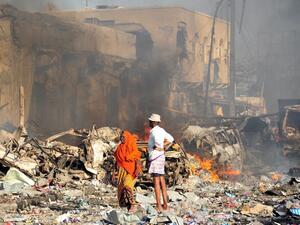 A man and woman look at the damages on the site of the explosion of a truck bomb in the centre of Mogadishu, on October 14, 2017 (Mohamed Abdiwahab/AFP)