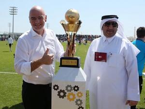 FIFA President Gianni Infantino (L) poses for a picture with the workers football cup trophy during a match ahead of a press conference in the Qatari capital Doha on April 22, 2016. 
KARIM JAAFAR / AFP