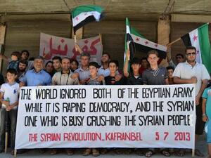  Syrian demonstrators posing with a banner referring to the situation in both Syria and Egypt during an anti-regime protest in Kfar Nubul in the northwestern province of Idlib (Shaam news network / AFP)