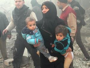 A Syrian woman carries children following airstrikes on a rebel area of the war-torn northern city of Aleppo on December 15, 2013. [AFP]