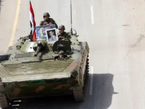 عناصر من الجيش السوري على ظهر مدرعة يرفعون صورا للرئيس بشار الأسد