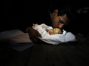 والد الطفلة التي ذهبت ضحية القصف الاسرائيلي على الزيتون بغزة،حنين طافش، 10 اشهر، يقبل جبينها قبل ان توارى في الثرى/أ.ف.ب