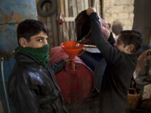 اطفال يعبأون ديزل للتدفئة في بلدة اعزاز شمال سوريا/أ.ف.ب