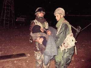 جنديان من حرس الحدود الاردني يساعدان مسنة سورية