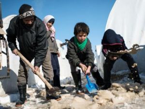 عائلة سورية تزيل الثلج من جوانب خيمتها في مخيم اعزاز شمالا/أ.ف.ب