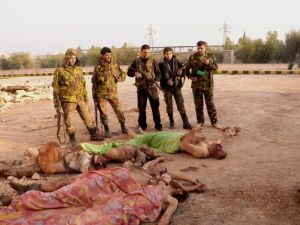 جنود من الجيش النظامي يقفون امام جثث مقاتلين من المعارضة بالقرب من حلب/أ.ف.ب