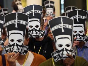 Delegates at a meeting of Amnesty International hold up masks depicting ancient Egyptian Queen Nefertiti wearing a gas mask in protest against the ongoing violence as well as sexual violence against women in Egypt on August 19, 2013. [ Getty Images]