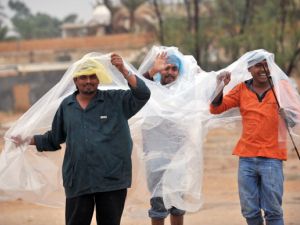 Foreign workers protect themselves from the rain while crossing a flooded street in the Saudi capital Riyadh on November 19, 2013. [AFP]
