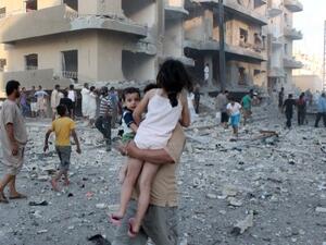 سوري يحمل طفليه مبتعدا عن مكان انفجار في مدينة الرقة/أ.ف.ب