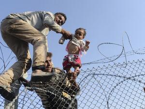 لاجئون سوريون يعبرون الاسلاك الشائكة باتجاه تركيا