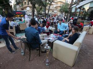 Syrian youths sit at a cafe in the government-held Mogambo neighbourhood of the northern Syrian city of Aleppo as they celebrate the Eid al-Adha Muslim holiday on September 13, 2016, a day after a fragile ceasefire was brokered. (AFP/Youssef Karwashan)