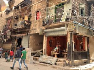 People walk past a damaged barbershop in a government-controlled district of the northern Syrian city of Aleppo on May 21, 2016. (AFP/George Ourfalian)