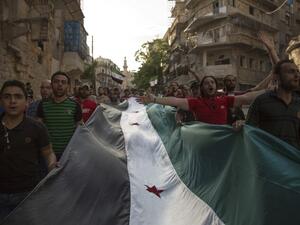 Syrians carry a giant pre-Baath Syrian flag as they shout slogans during an anti-regime protest in the rebel-held Bustan al-Qasr district in eastern Aleppo on May 5, 2016. (AFP/Karam al-Masri)