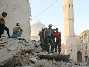 Syrian civil defense volunteers, known as the White Helmets, carry the body of a victim following a government forces air strike on the rebel-held neighborhood of Bustan al-Basha in the northern city of Aleppo, on October 4, 2016. (AFP/Thaer Mohammed)