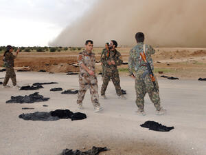 Fighters from the Syrian Democratic Forces stand amongst black abyays discarded by women escaping Daesh territory. (AFP/Ayham al-Mohammad)