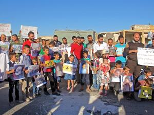 Syrians gather on July 12, 2017 with pictures of victims of a suspected toxic gas attack (Omar haj kadour/AFP)