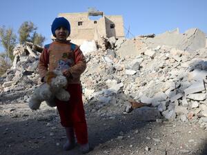 A Syrian girl, holding her stuffed toy, stands next to the rubble of buildings in the northwestern Syrian border town of al-Bab on February 25, 2017. (AFP/Nazeera al-Khatib)