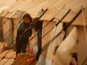 A displaced Syrian girls looks on during a sand storm at the al-Mabrouka camp in the village of Ras al-Ain on the Syria-Turkey border, where many Syrians who fled from territory held by the Islamic State (IS) group in Deir Ezzor and Raqa are taking shelter on April 23, 2017. (AFP/Delil Souleiman)