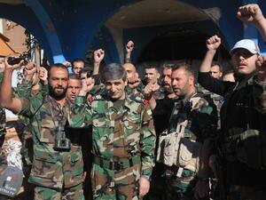 Members of the Syrian Army celebrate reclaiming the Kweires airbase earlier this week, shortly before recapturing Al-Hader, also in Aleppo. (AFP/George Ourfalian)