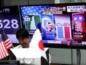 A currency trader in Tokyo observes progress in the US presidential election as a TV channel displays portraits of contenders Hillary Clinton and Donald Trump. (AFP)