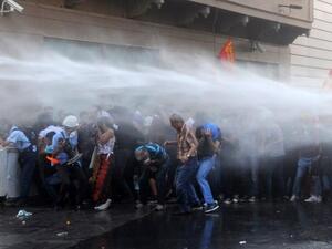 Protesters take cover from a water cannon during clashes with police on Istiklal Avenue in Istanbul on July 6 (AFP)