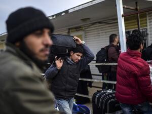 Syrian people wait in front of the Oncupinar crossing gate to go back to Syria, near the town of Kilis, in south-central Turkey, on February 11, 2016. (AFP/Bulent Kilic)