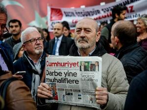 A protester holds a copy of Cumhuriyet newspaper during a protest in front of the opposition newspaper in Istanbul on October 31, 2016 after a police operation at the daily's headquarters. (AFP/Ozan Kose)