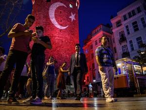 People take pictures on a street near the Galata Tower, illuminated in Turkish flag colors on August 1,2016 at Galata district in Istanbul. (AFP/Ozan Kose)