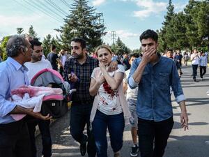 An injured woman, next to a man carrying her baby, walks near the site where a bomb explosed on May 10, 2016 in Diyarbakir. Three people were killed and 22 wounded in the attack. (AFP/Ilyas Akengen)