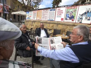 People sit next to campaign posters for parliamentary elections at a cafe in the northern part of Nicosia in the Turkish Republic of Northern Cyprus on January 3, 2018. (AFP/ File)
