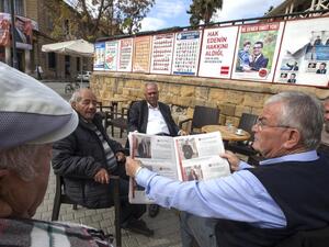 People sit next to campaign posters for parliamentary elections at a cafe in the northern part of Nicosia in the Turkish Republic of Northern Cyprus on January 3, 2018. (AFP/ File)
