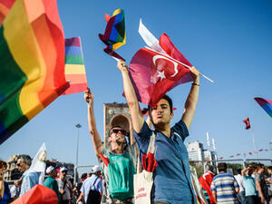 People wave LGBT rainbow flags at Istanbul's Taksim Square as they take part in a political demonstration on 24 July 2016 (AFP)