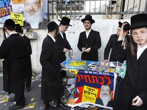 Ultra-Orthodox Jewish men stand next to campaign posters of municipal candidate Yossi Daitch outside a polling station, in Jerusalem on October 30, 2018. (MENAHEM KAHANA / AFP)